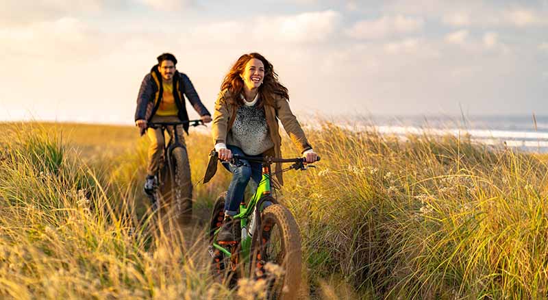 Two people riding bikes near the coast