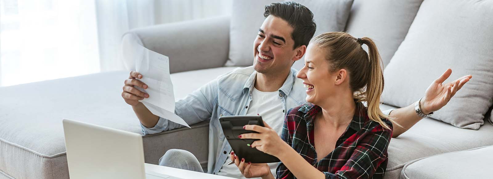 Man and women sitting in front of computer looking at a paper