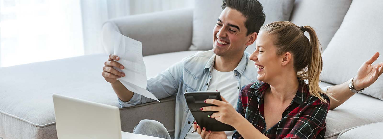 Man and women sitting in front of computer looking at a paper