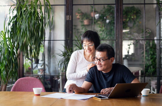 Couple looks at paper and laptop together