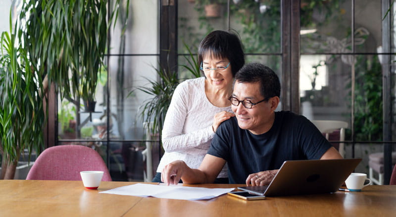Couple looks at paper and laptop together