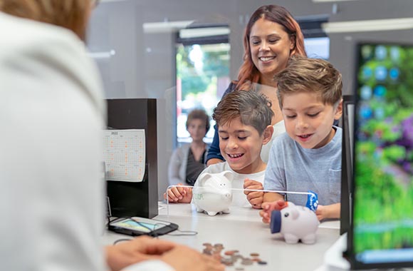 Two kids depositing piggy bank coins