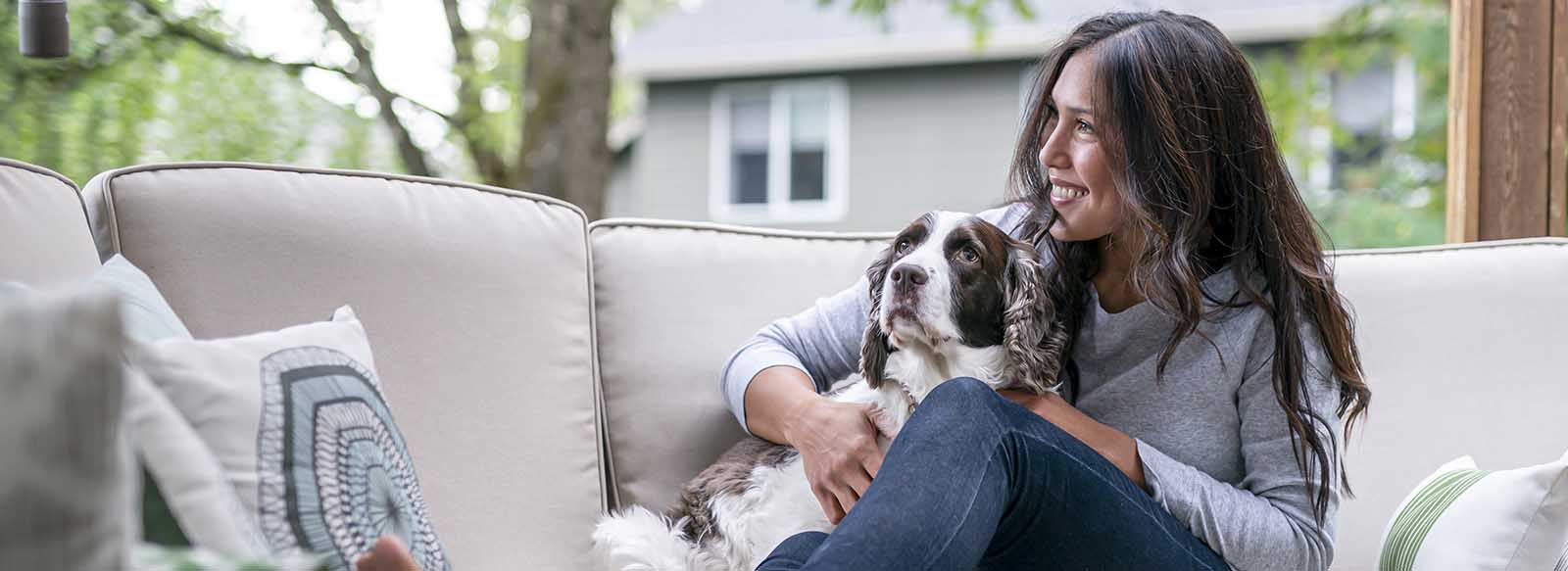 Person sitting on couch outside of home with dog