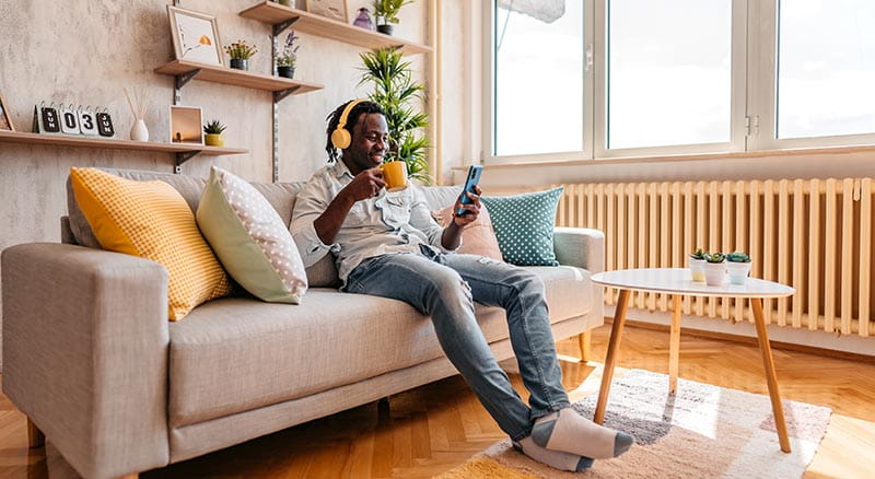 Man with headphones on sitting and looking at phone