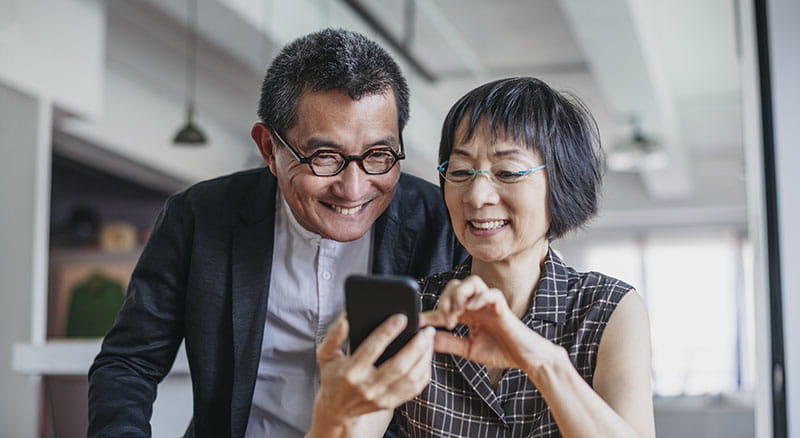 Man looking over woman's shoulder at phone