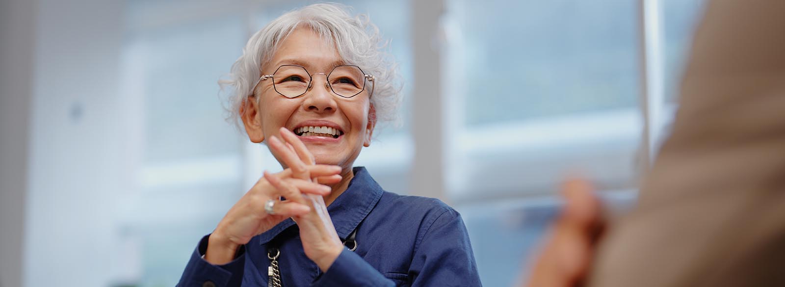 Person smiling with folded hands on table