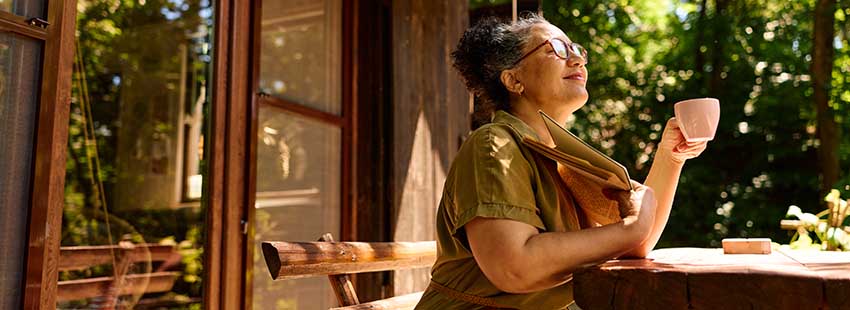 Person on porch with mug and book in hand