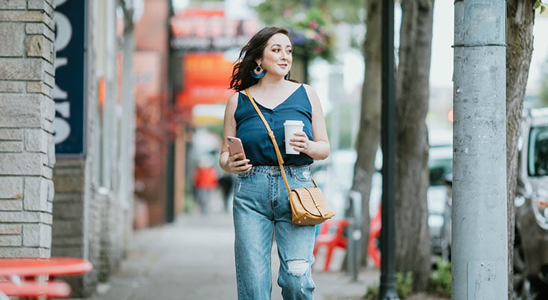 Woman walking with coffee cup and phone